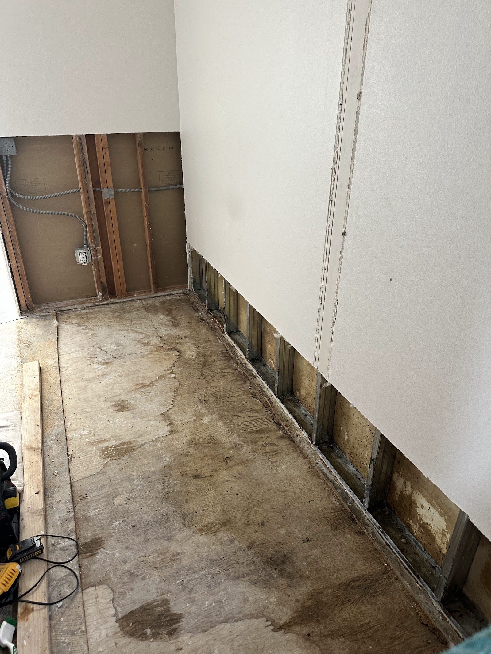 Hallway with lower drywall removed to expose wet framing