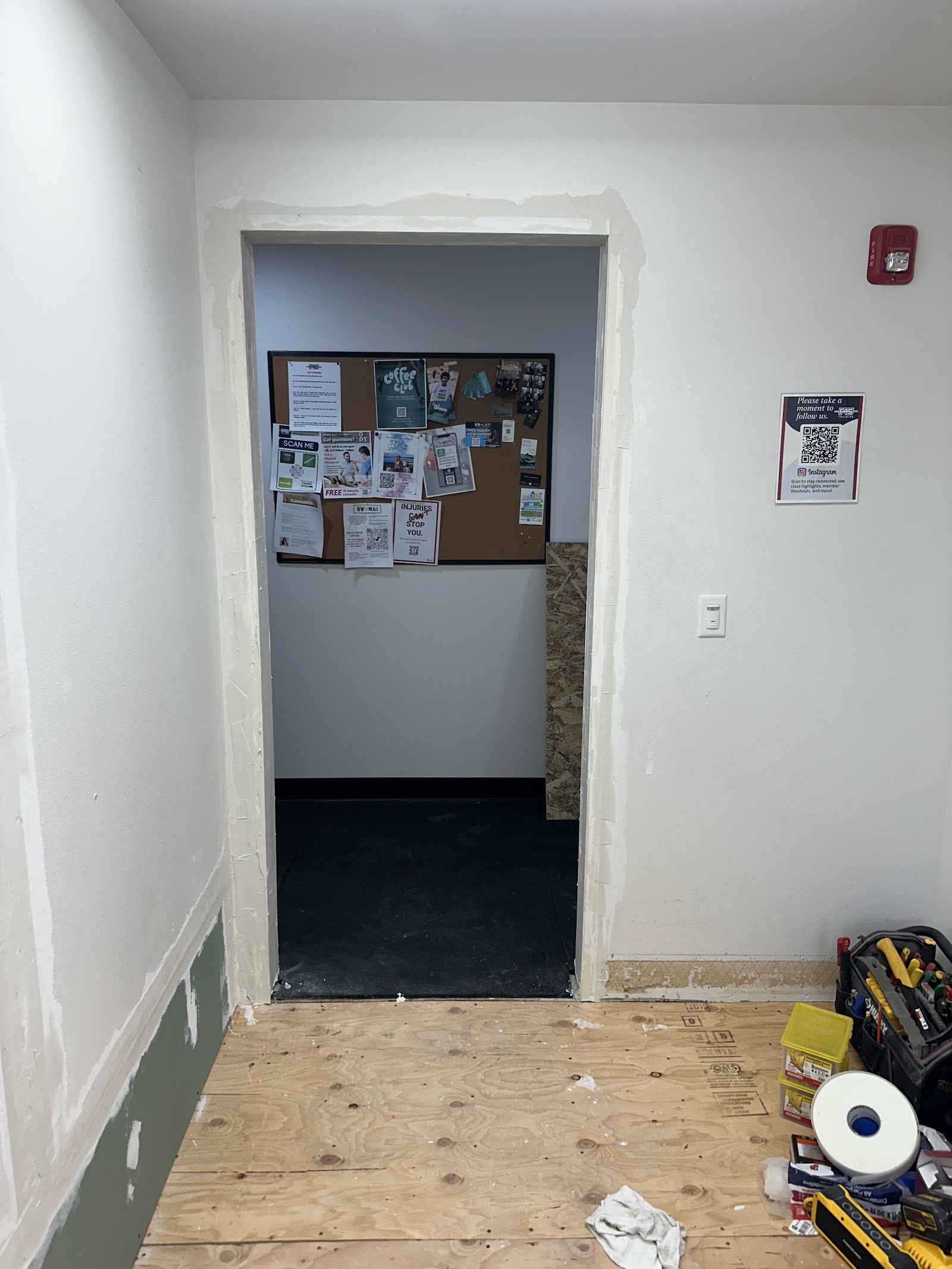 Hallway doorway with new drywall patching and plywood floor