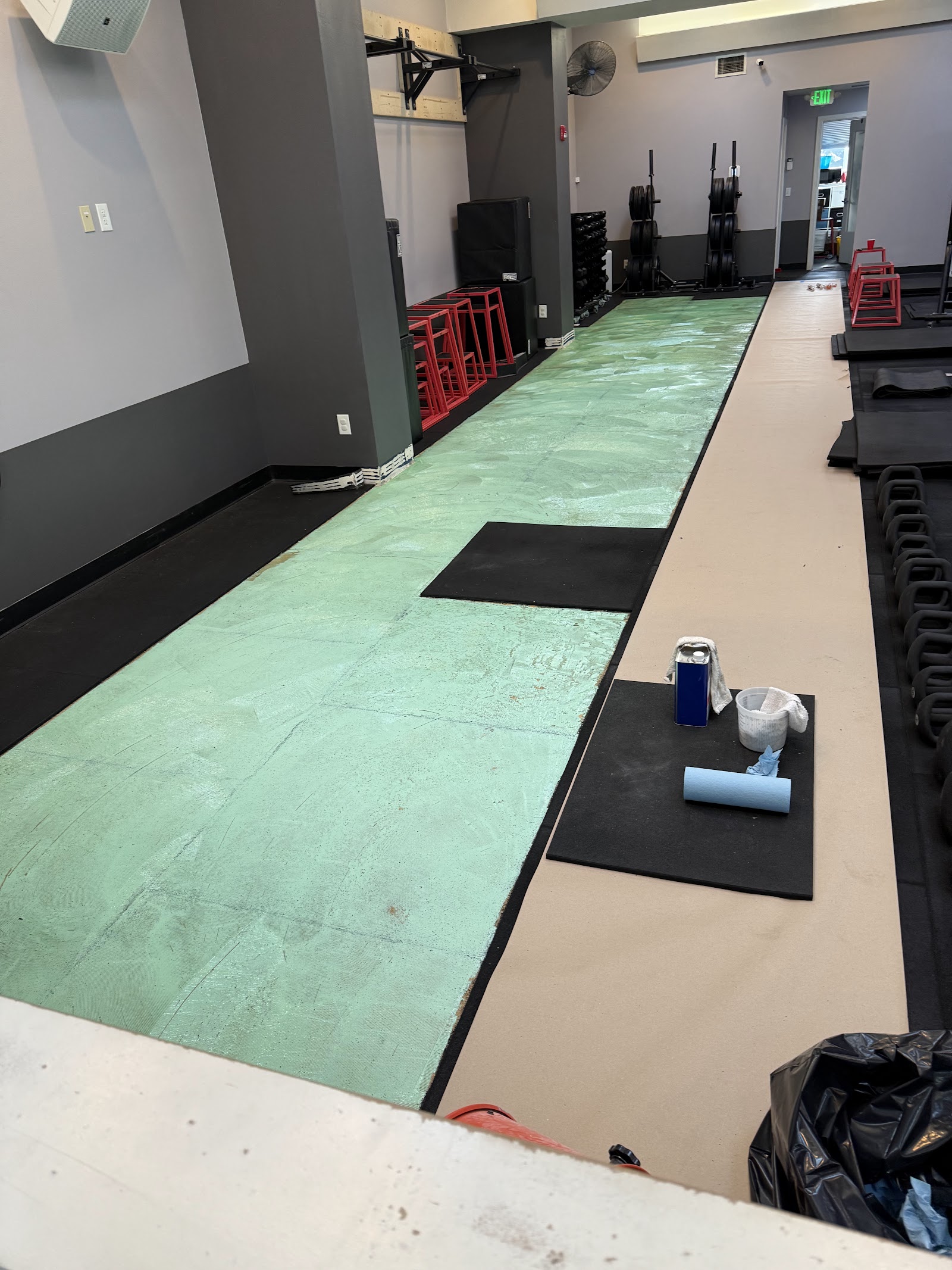 Training floor mid-renovation with old flooring removed and equipment staged aside