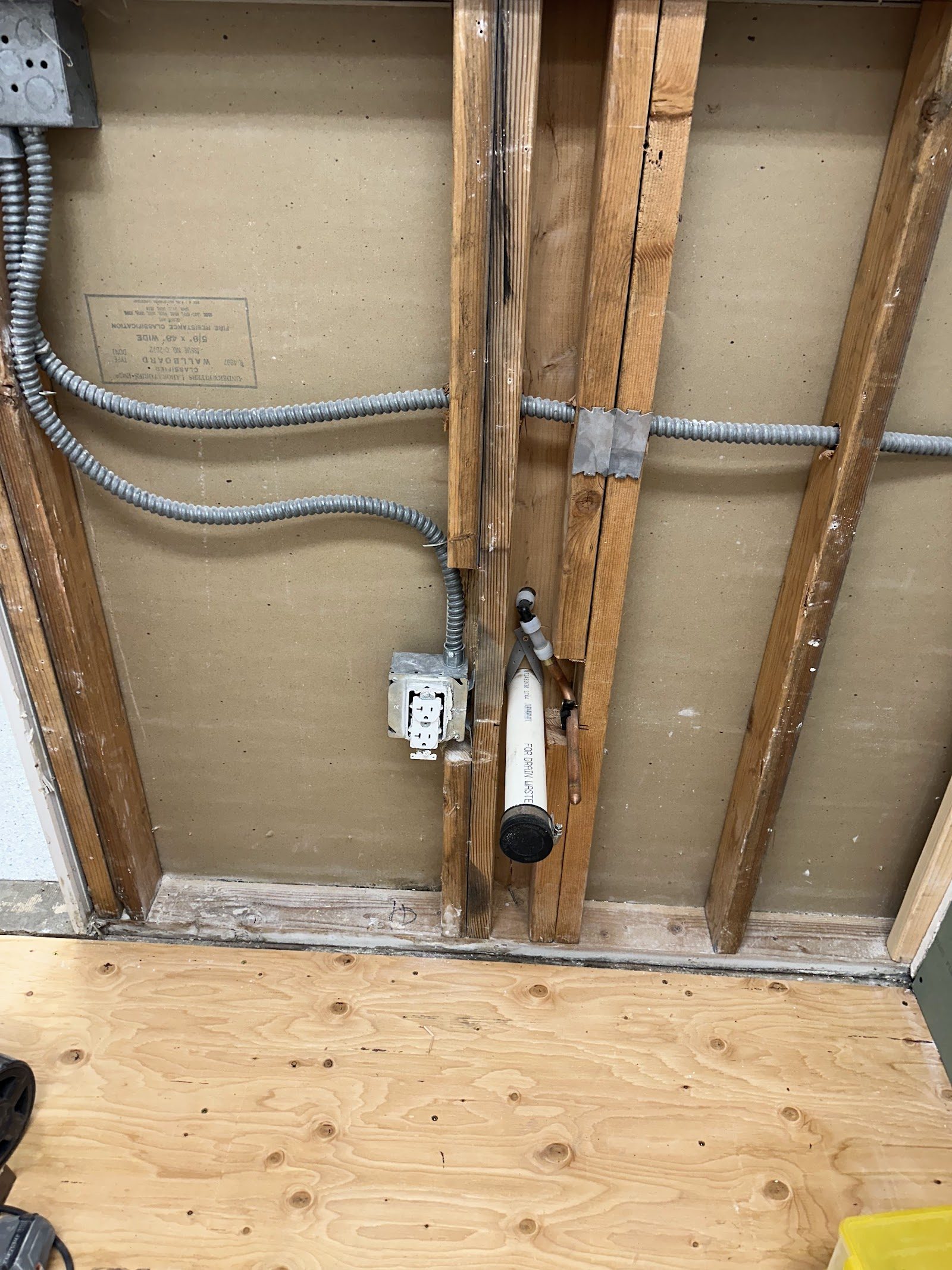 Exposed wall cavity with electrical conduit and new plumbing line