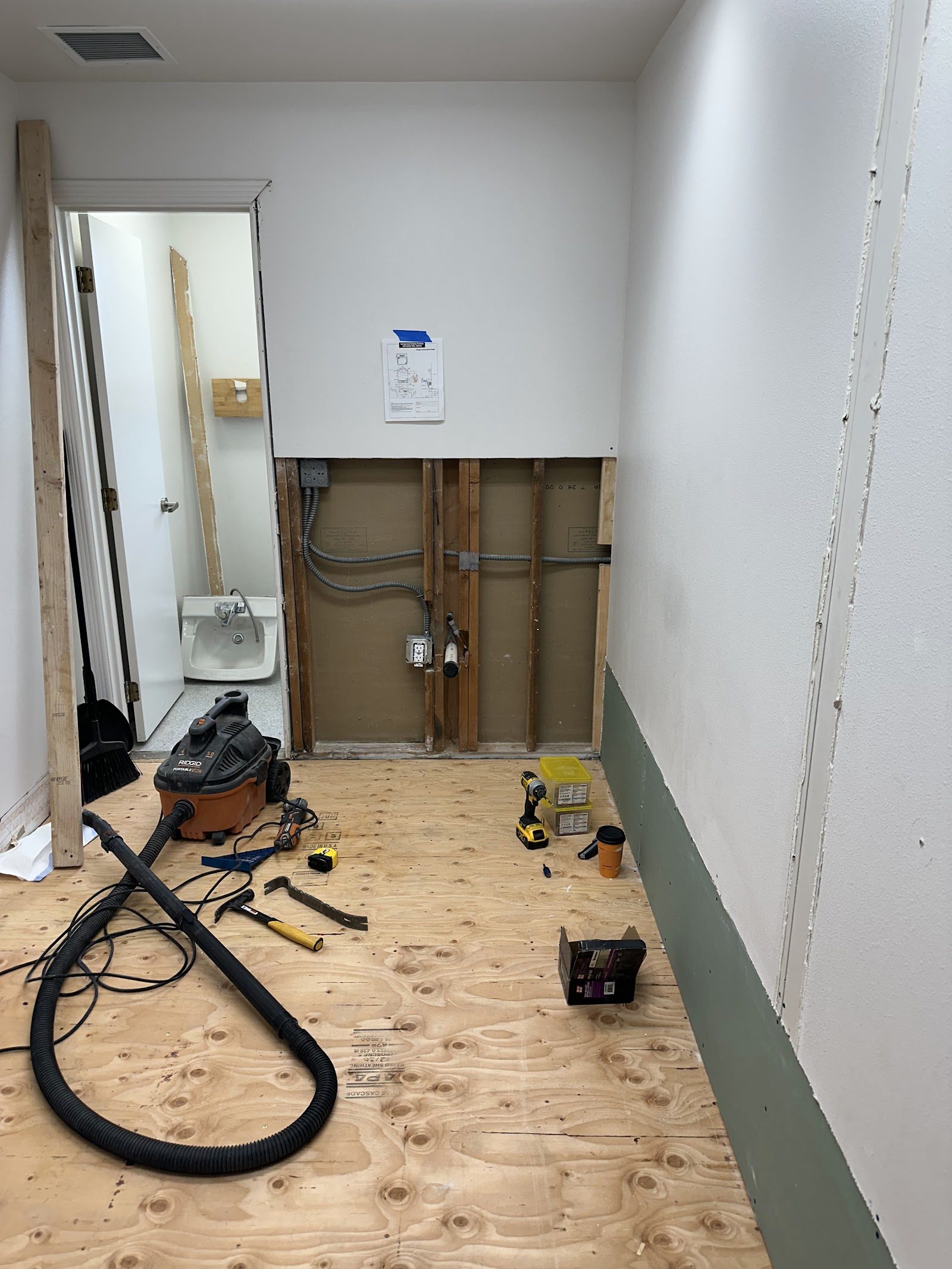 Hallway opened up with new plywood subfloor and exposed wall framing
