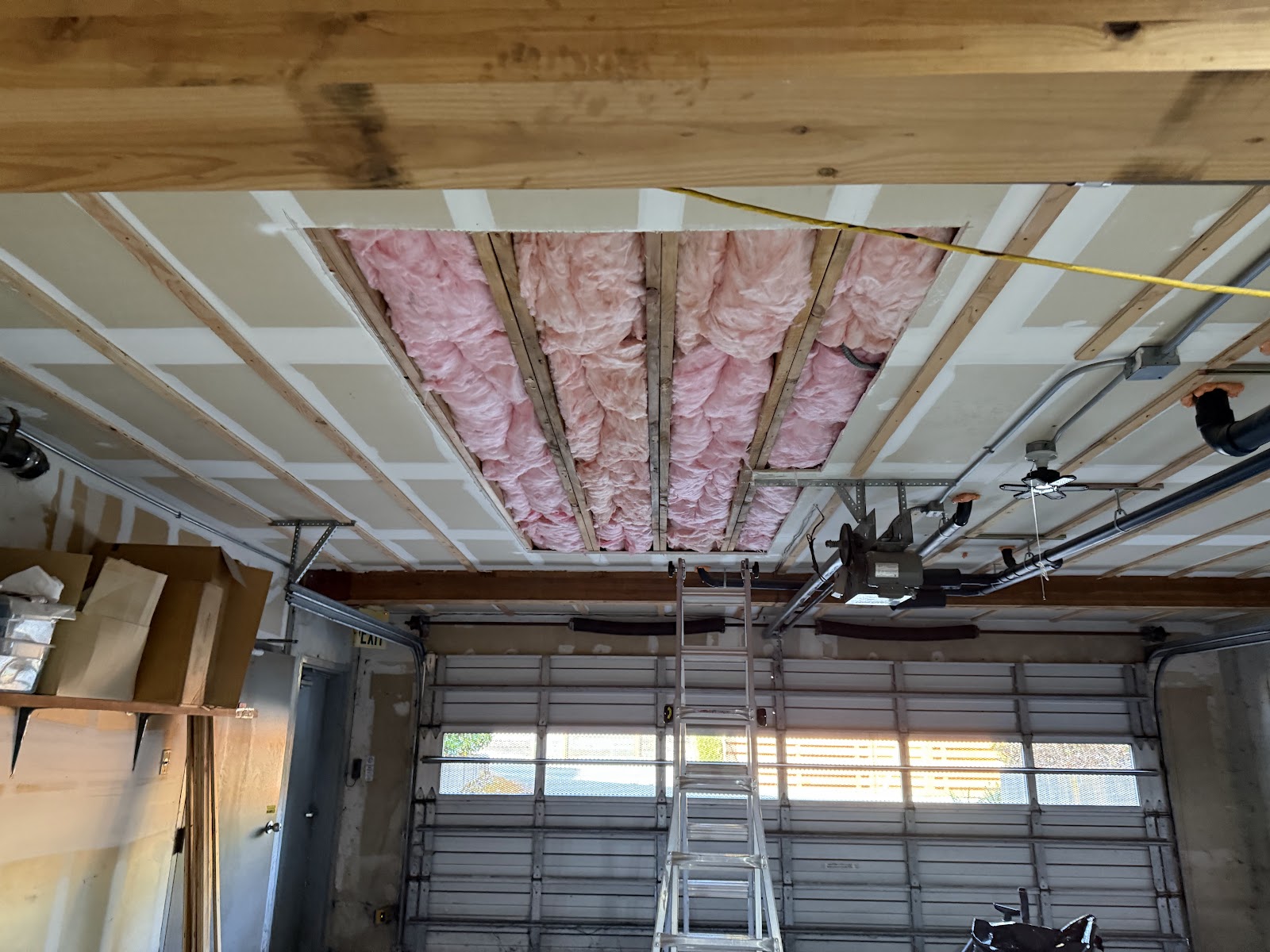 Opened ceiling bay with insulation exposed above the garage door